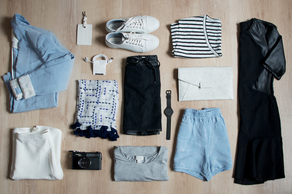 capsule wardrobe A collection of clothes and accessories laid out on a wooden floor.